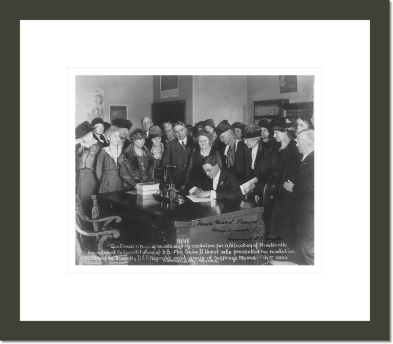 Gov[ernor] Emmett D. Boyle of Nevada signing resolution for ratification of Nineteenth Amendment to Constitution of U.S. - Mrs. Sadie D. Hurst who presented the resolution, Speaker of the Assembly D.J. Fitzgerald and group of Suffrage Women, Feb. 7, 1920, Carson City, Nevada