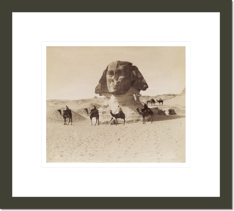 The head of the Sphinx rising from the sand with camel riders in the foreground